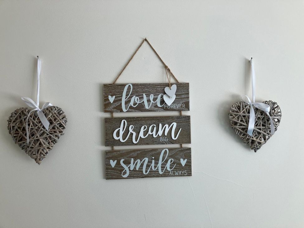 A decorative wall with a sign and heart shapes at Claire Cottage