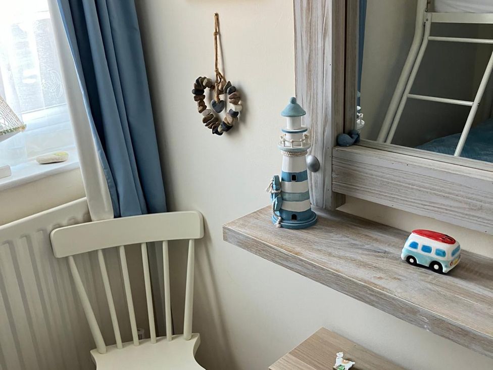 A bedroom with a chair, mirror, and decorative items at Claire Cottage