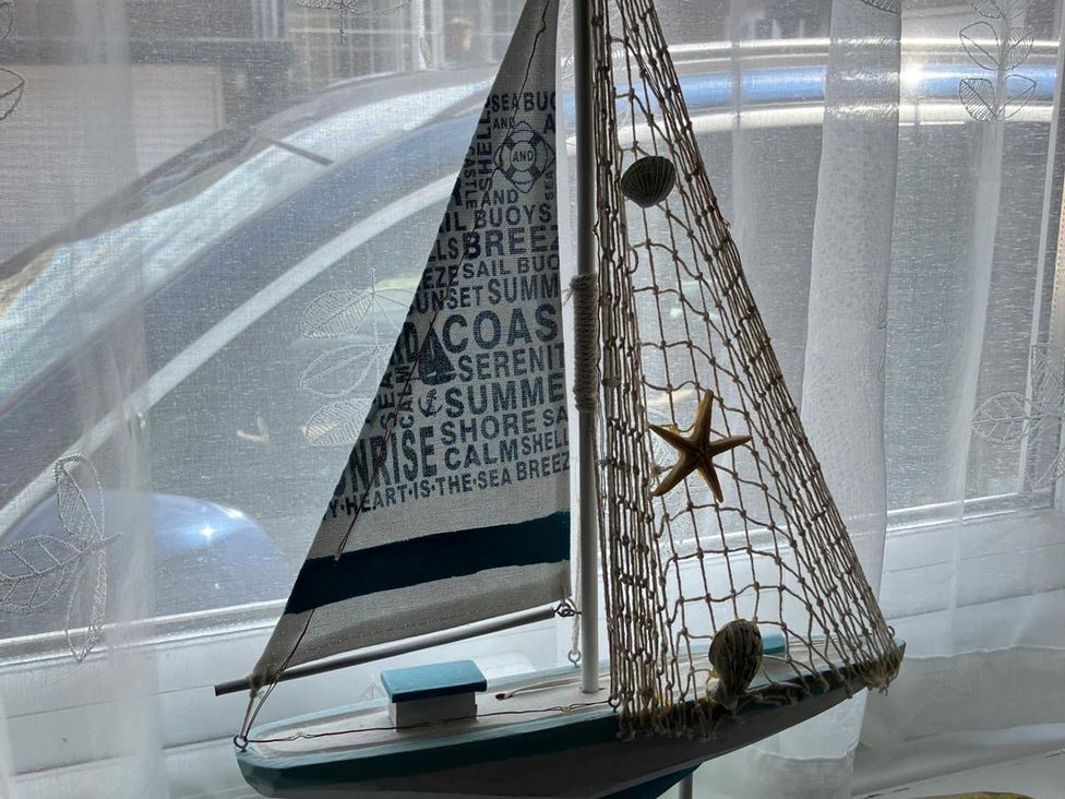 A decorative sailboat with starfish and netting near a window at Claire Cottage