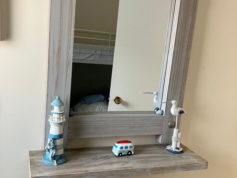 A mirror with decorative items on a shelf in Claire Cottage