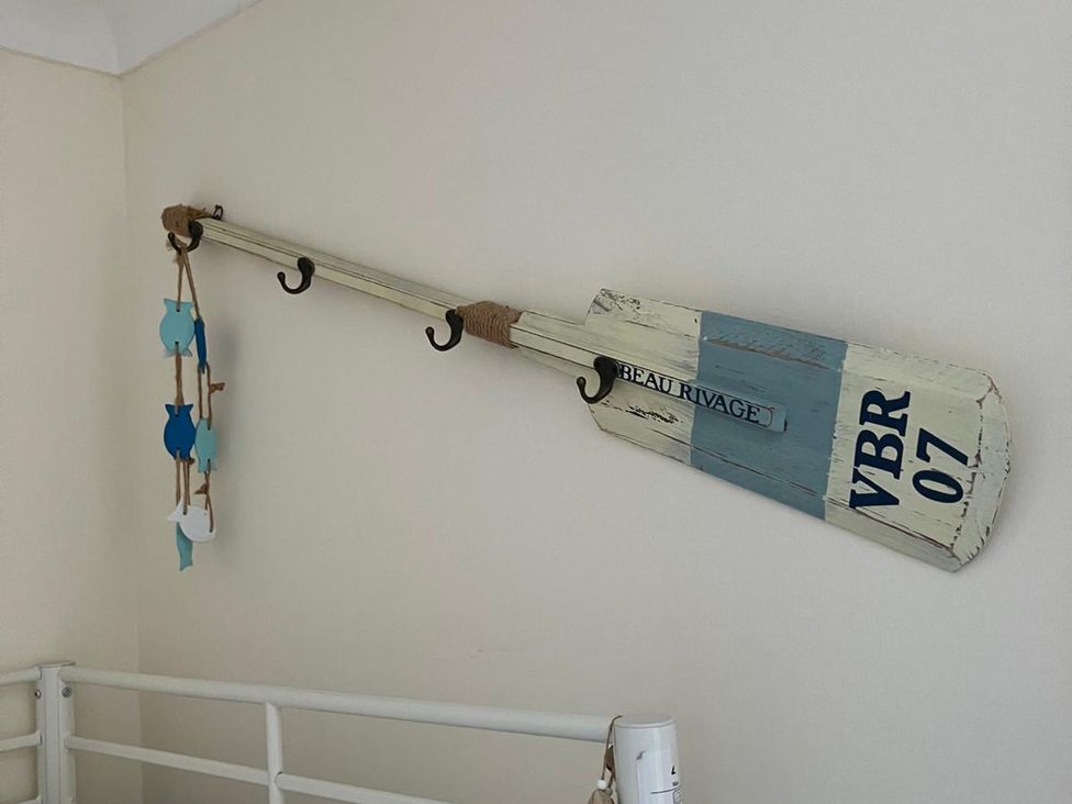 An oar with fish decorations and wall hooks at Claire Cottage