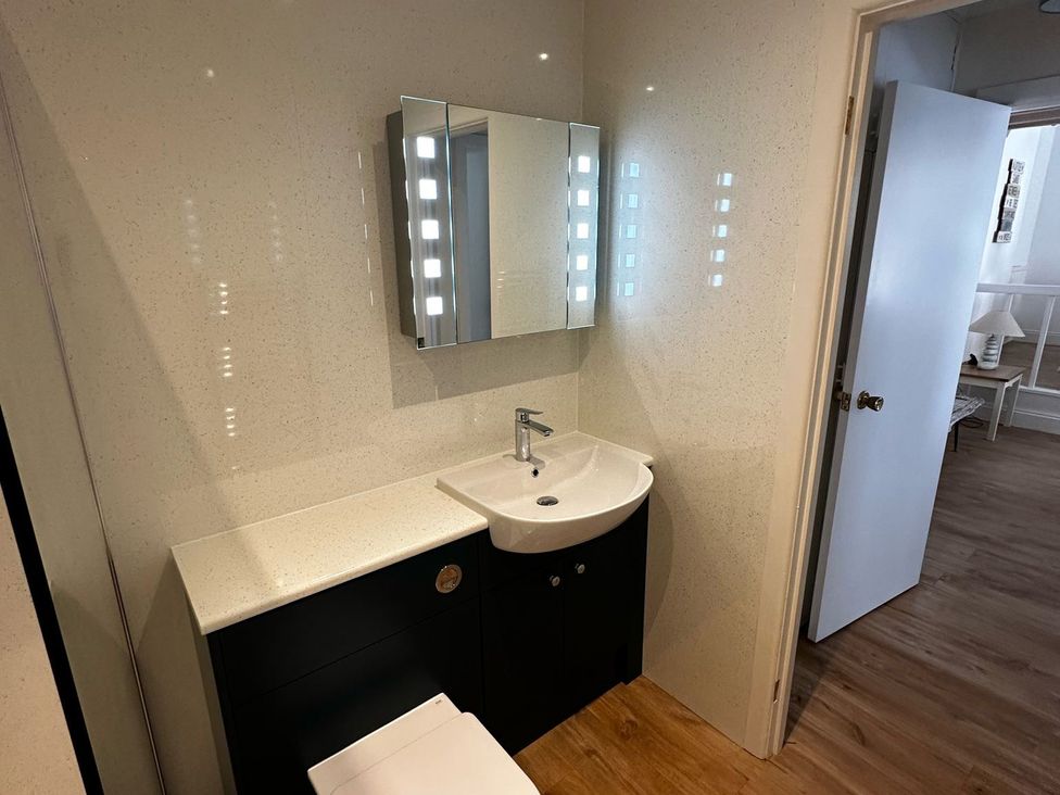 A bathroom with a sink, toilet, and mirror at Claire Cottage