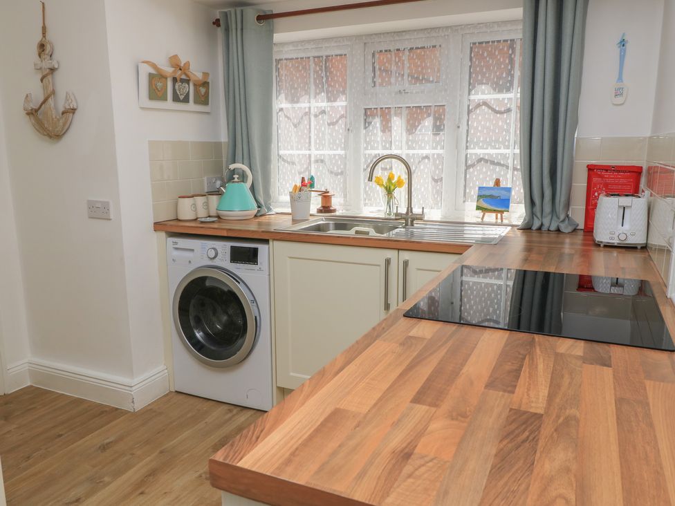 A kitchen with a washing machine and sink at Claire Cottage in Swanage