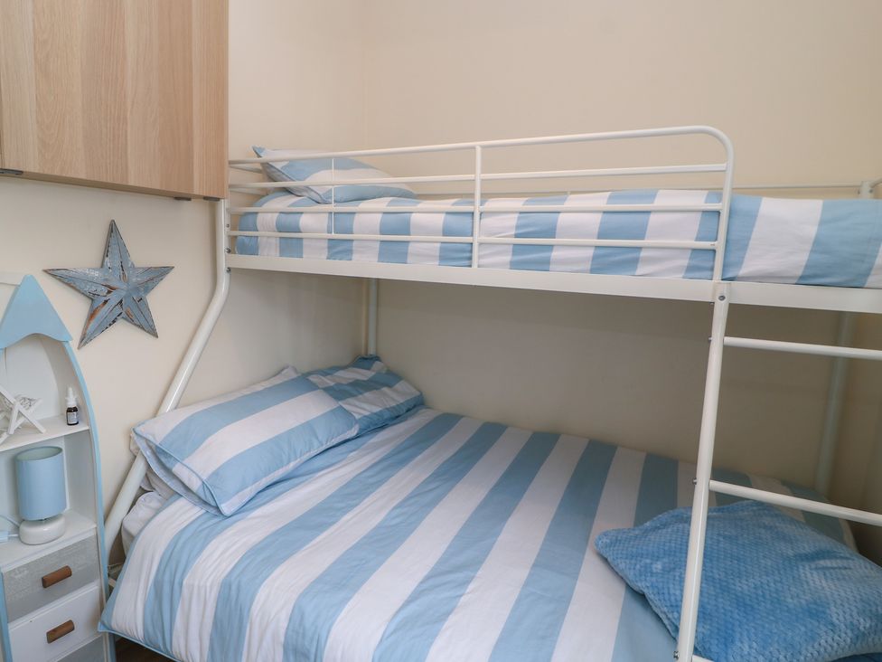 A bedroom with a bunk bed and a single bed at Claire Cottage in Swanage