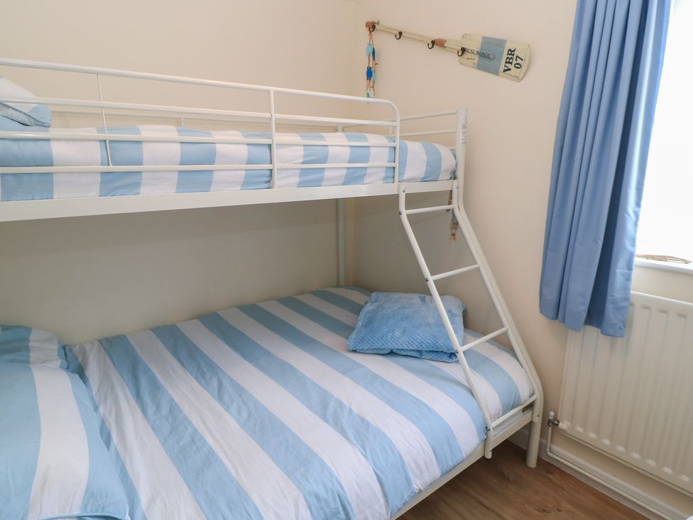 A bedroom with a bunk bed and blue striped bedding at Claire Cottage in Swanage