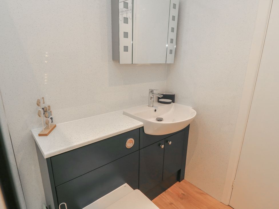 A bathroom with a sink, mirror, and cabinet at Claire Cottage in Swanage