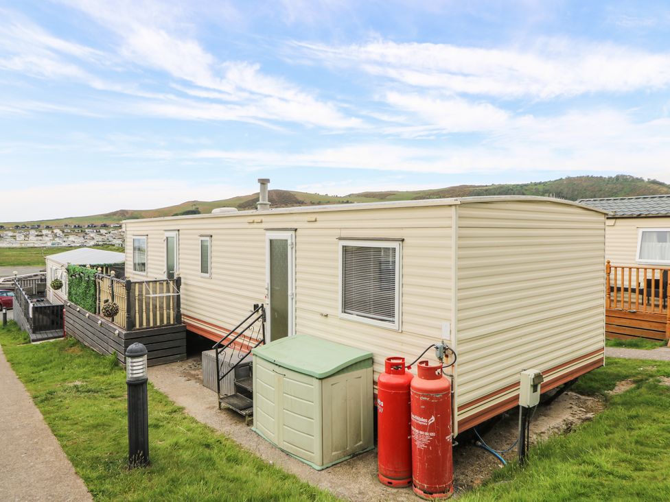 A beige mobile home with steps leading to a door and two red gas cylinders outside at GM18 in Clarach Bay near Aberystwyth