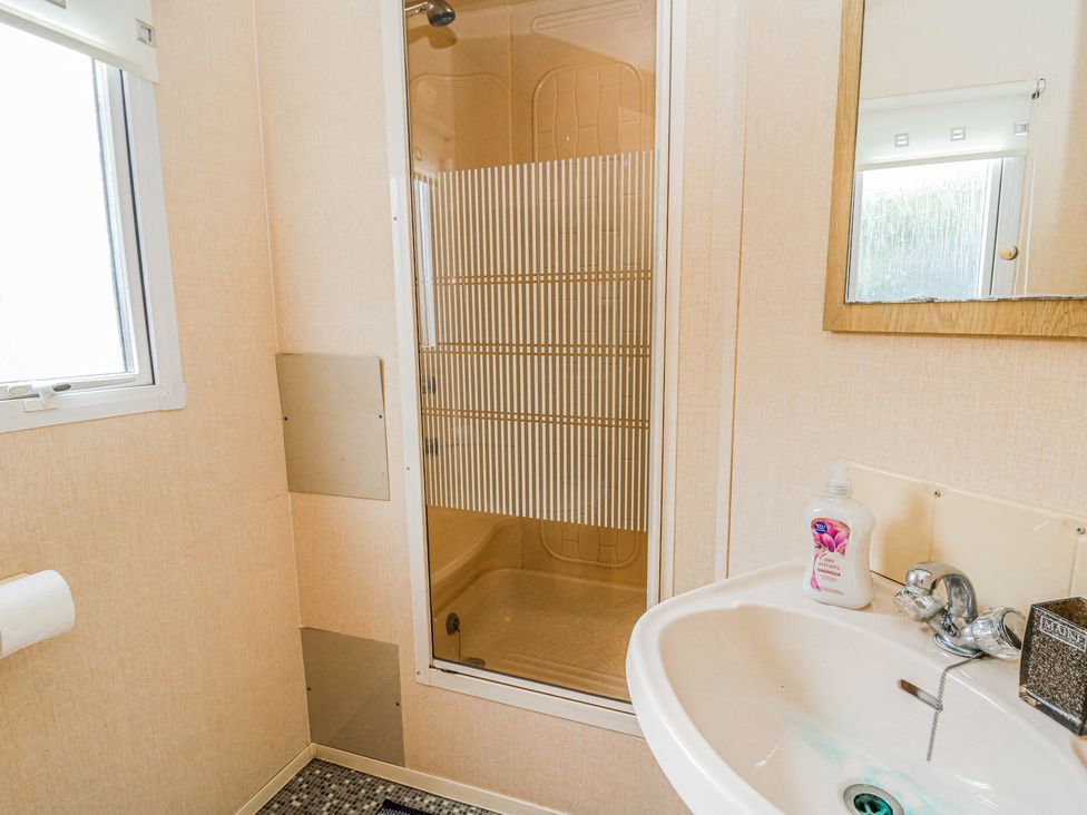 A bathroom with a shower cubicle sink and a window at GM18 in Clarach Bay near Aberystwyth