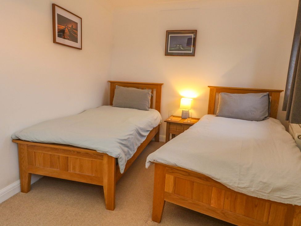 A bedroom with twin beds and a lamp on a bedside table at Corner Cottage Preston