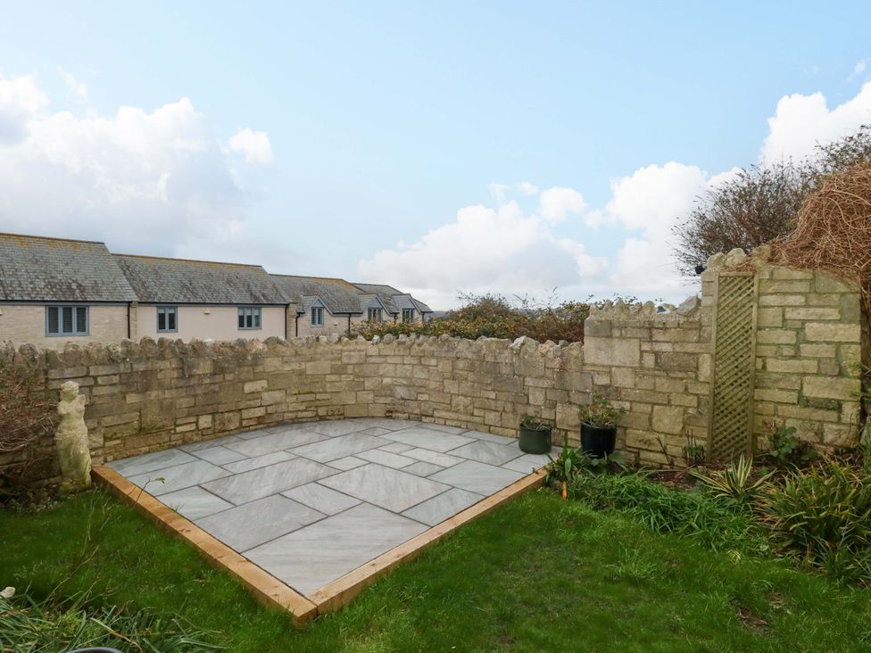 A garden with a stone wall and patio at Corner Cottage in Preston