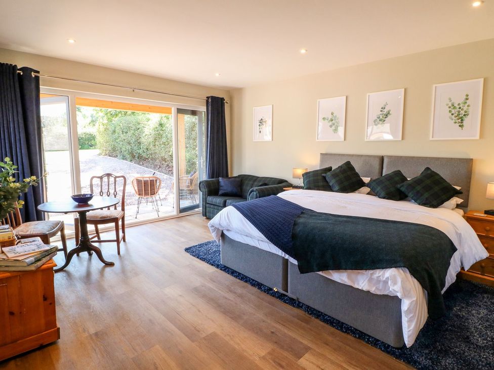 A bedroom with a bed and chairs at The Lodge at Middleton House Stoke-on-Trent