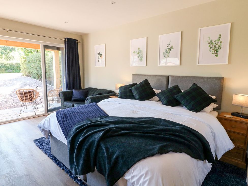 A bedroom with a bed and armchair at The Lodge at Middleton House Stoke-on-Trent
