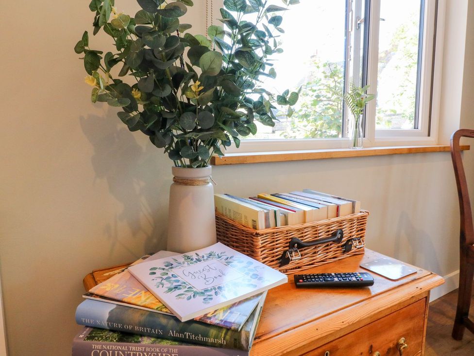 A living room with a table, books, and a plant at The Lodge at Middleton House in Stoke-on-Trent