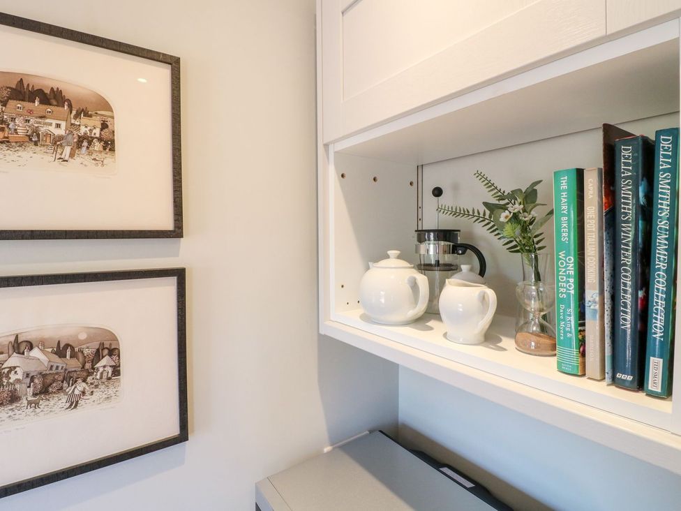 A kitchen shelf with a teapot, coffee maker, and books at The Lodge at Middleton House Stoke-on-Trent