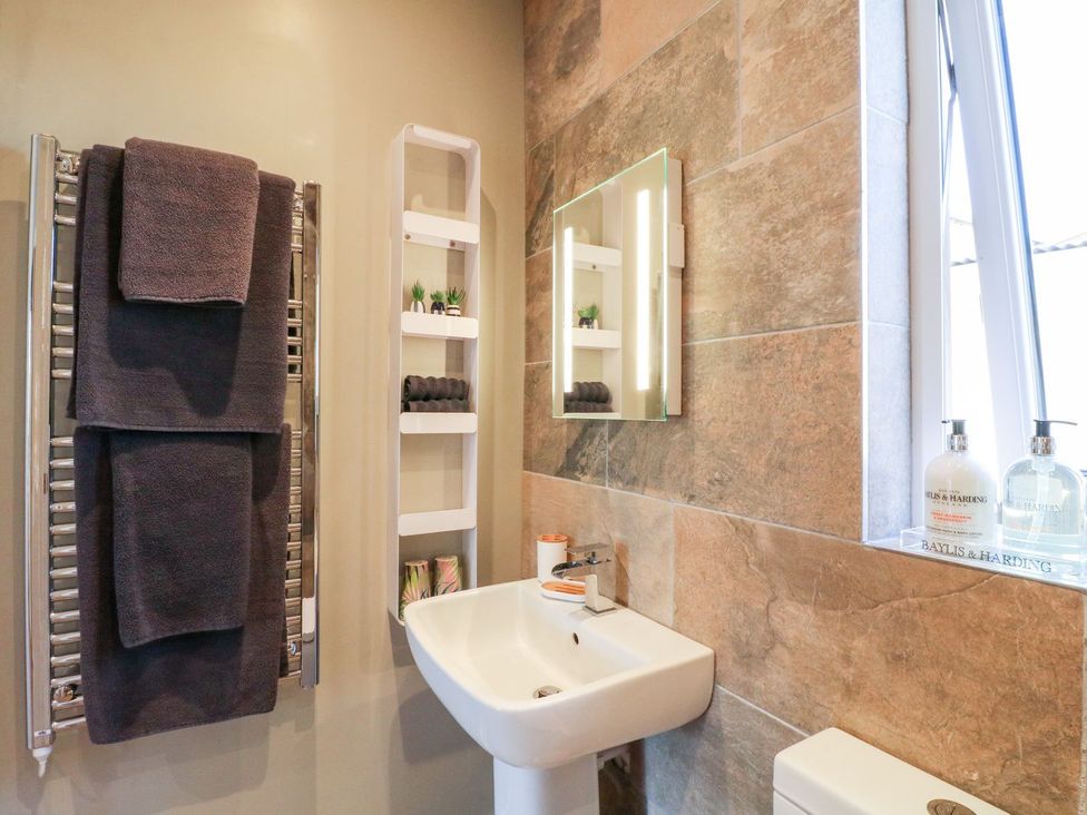 A bathroom with a towel radiator, sink, toilet, and mirror at The Lodge at Middleton House Stoke-on-Trent