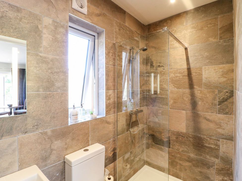 A bathroom with a shower and mirror at The Lodge at Middleton House Stoke-on-Trent
