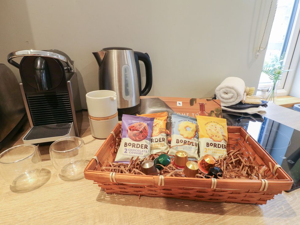 A kitchen setup with kettle, coffee machine, cups, cookies in a basket at The Lodge at Middleton House Middleton Green near Stone