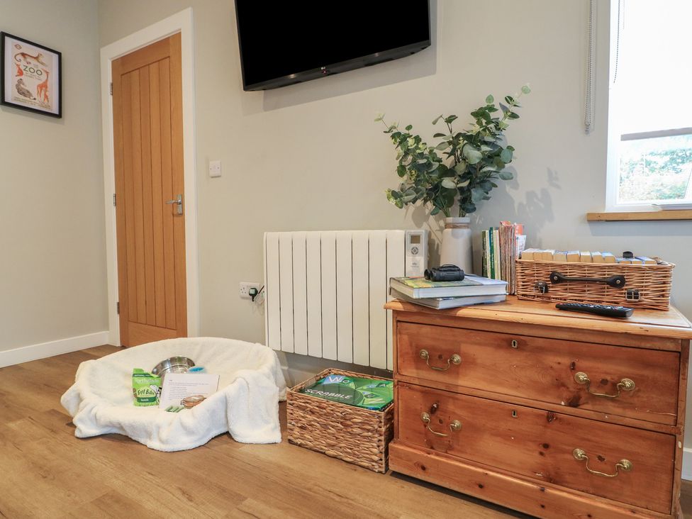 A living room with a television and pet bed at The Lodge at Middleton House in Middleton Green near Stone