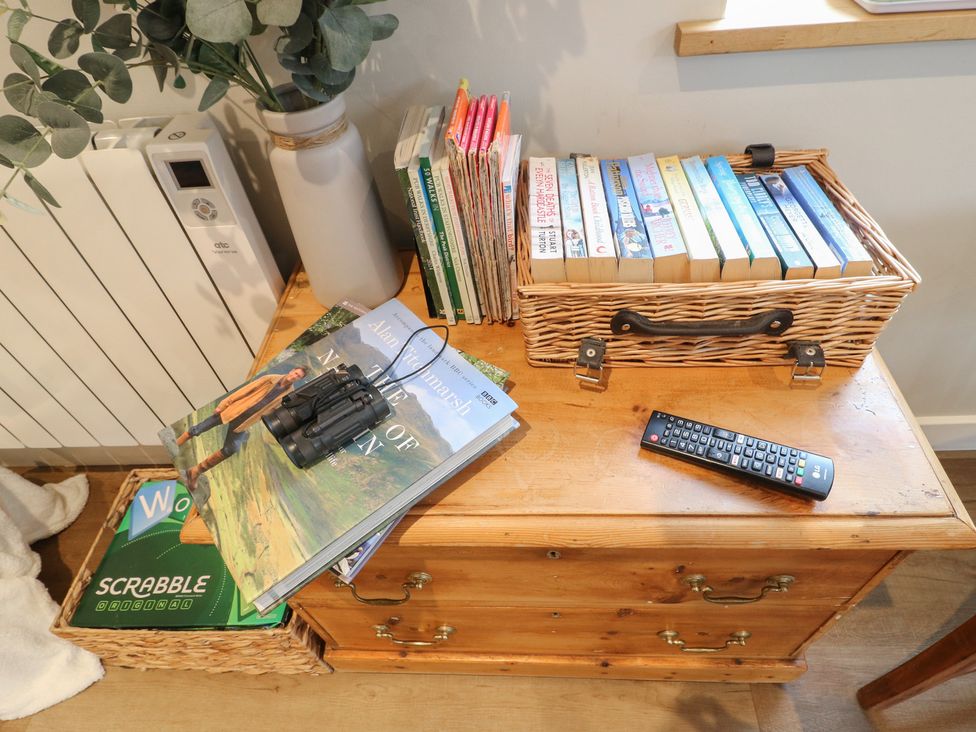 A living room with books, binoculars, and a remote at The Lodge at Middleton House Middleton Green near Stone