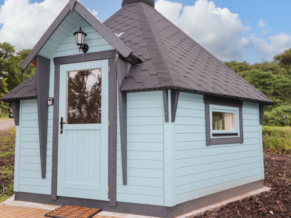 A small blue building with a sloped roof and a front door at Little Luxe Lodges Balmacara near Kyle of Lochalsh