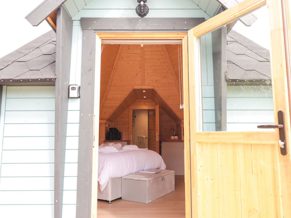 A bedroom with a bed and kitchen area at Little Luxe Lodges in Balmacara near Kyle of Lochalsh