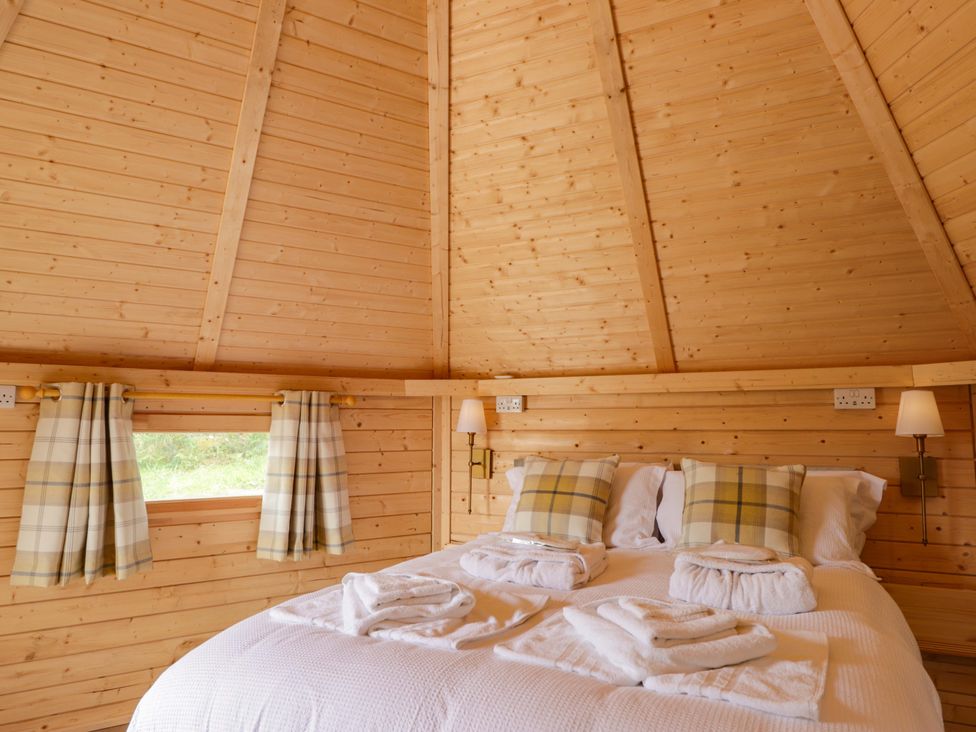 A bedroom with a double bed and wooden walls at Little Luxe Lodges Balmacara near Kyle of Lochalsh