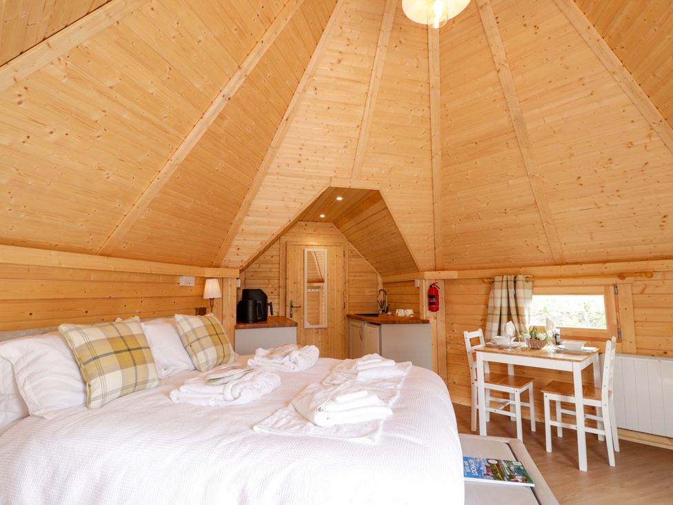 A bedroom with a bed and a dining area at Little Luxe Lodges Balmacara near Kyle of Lochalsh