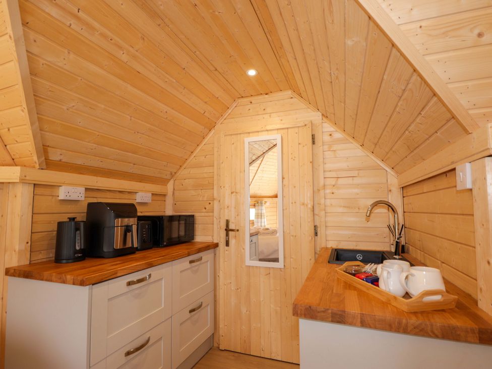 A kitchen with wooden cabinets and appliances at Little Luxe Lodges Balmacara near Kyle of Lochalsh