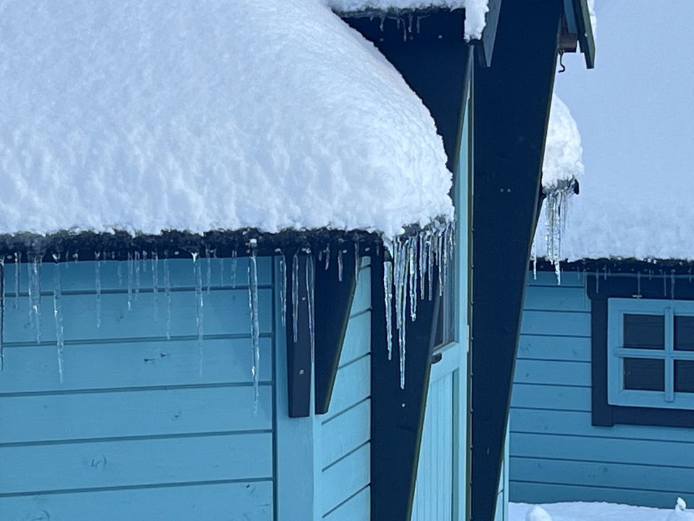 A wooden building with snow on the roof and icicles hanging at Little Luxe Lodges 1 Balmacara near Kyle of Lochalsh