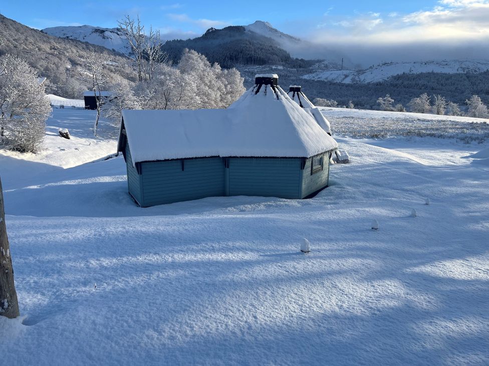 A cabin in snow with mountains in the background at Little Luxe Lodges 2 Balmacara near Kyle of Lochalsh
