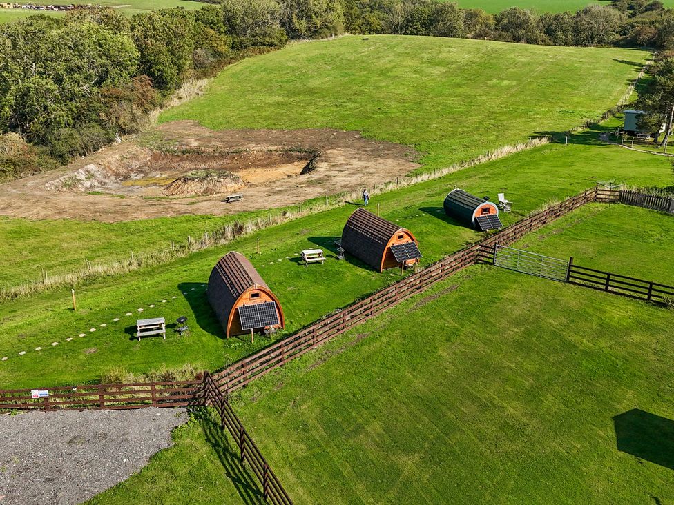 An outdoor area with camping pods and benches at Woodpeckers Shepherds hut Staintondale near Burniston