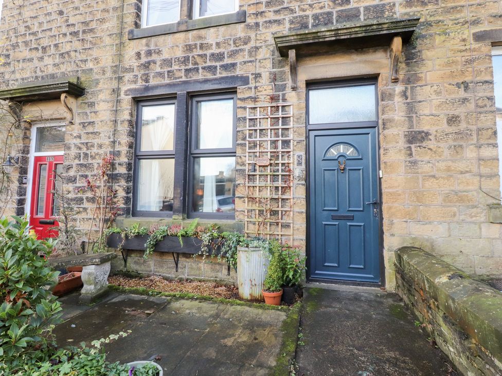 A front entrance with a blue door and plants at Heathcliff Cottage