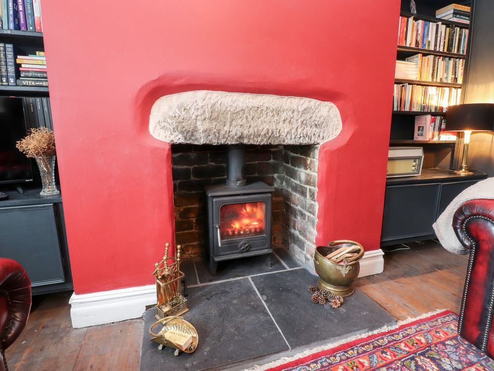 A living room with a fireplace and bookshelves at Heathcliff Cottage