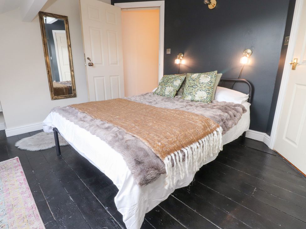 A bedroom with a bed, mirror, and door at Heathcliff Cottage