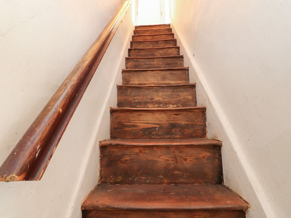 A staircase with wooden stairs and a handrail at Heathcliff Cottage