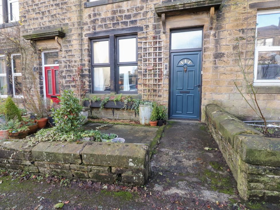 A front entrance with red and blue doors and stone wall at Heathcliff Cottage