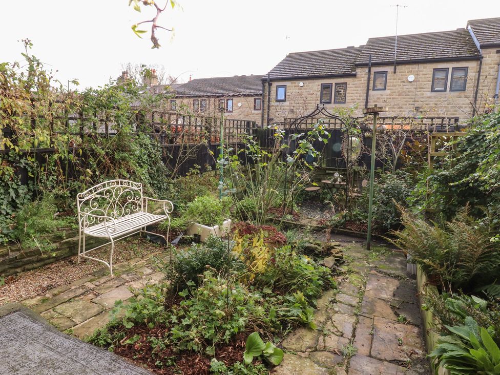 A garden with a stone pathway and a bench at Heathcliff Cottage