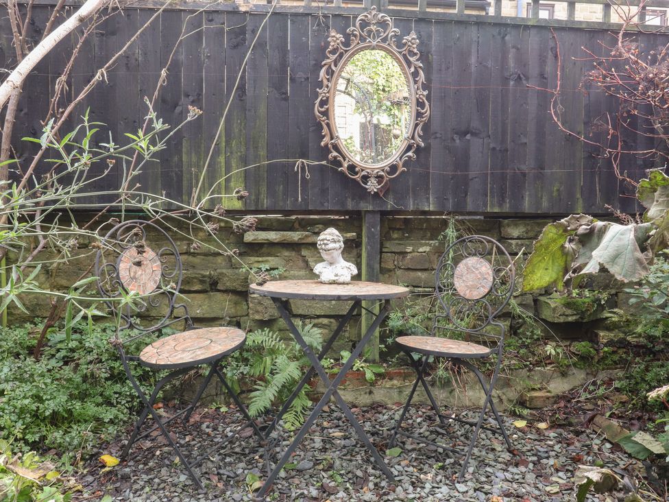 A garden with a table and chairs and a mirror at Heathcliff Cottage 