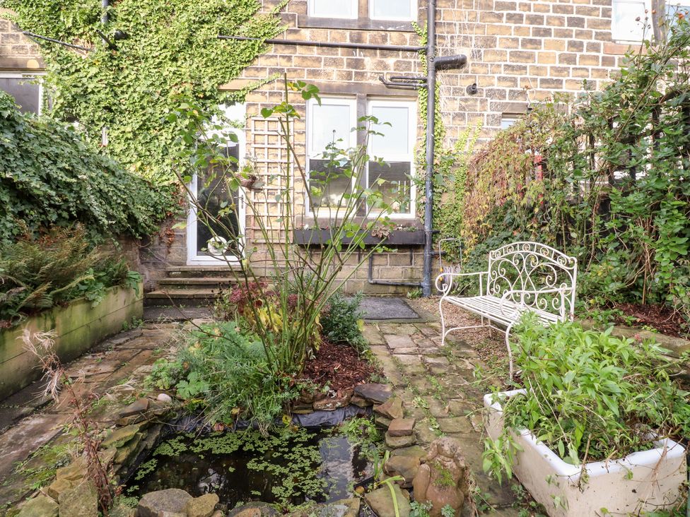 A garden with a pond and a bench at Heathcliff Cottage