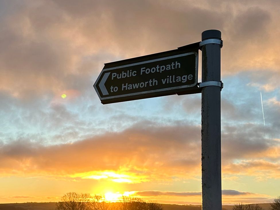 A directional sign pointing to Haworth village at sunset