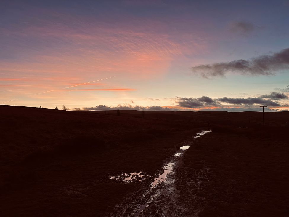A path with puddles under a cloudy sky at Heathcliff Cottage in Haworth