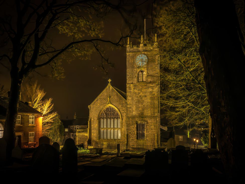 A church with clock tower and gravestones at Heathcliff Cottage in Haworth