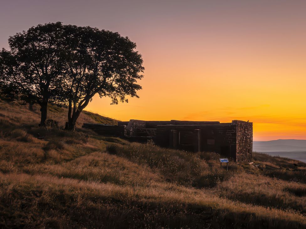 A building near a tree and grass at Heathcliff Cottage in Haworth
