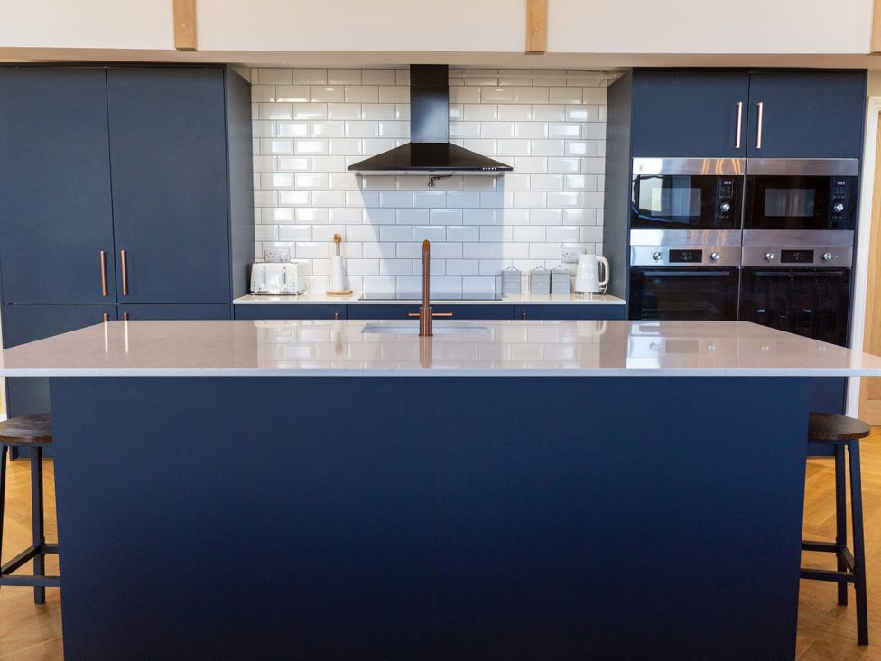 A kitchen with a blue island and appliances at Moorsholm View in Saltburn-by-the-Sea