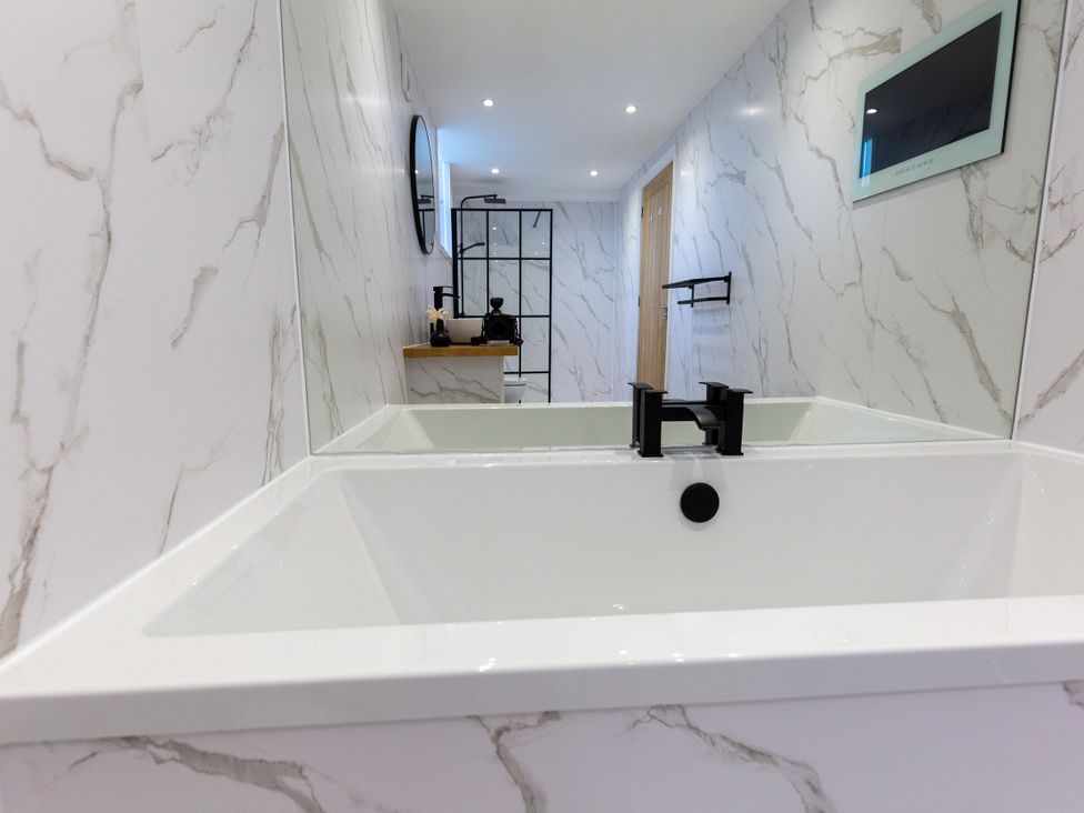 A bathroom with a bath tub and mirror at Moorsholm View in Saltburn-by-the-Sea