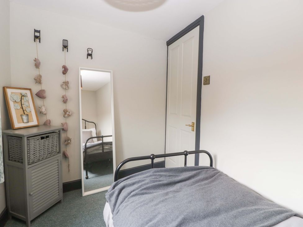 A bedroom with a bed and a mirror at Elm Cottage in Moreton-In-Marsh