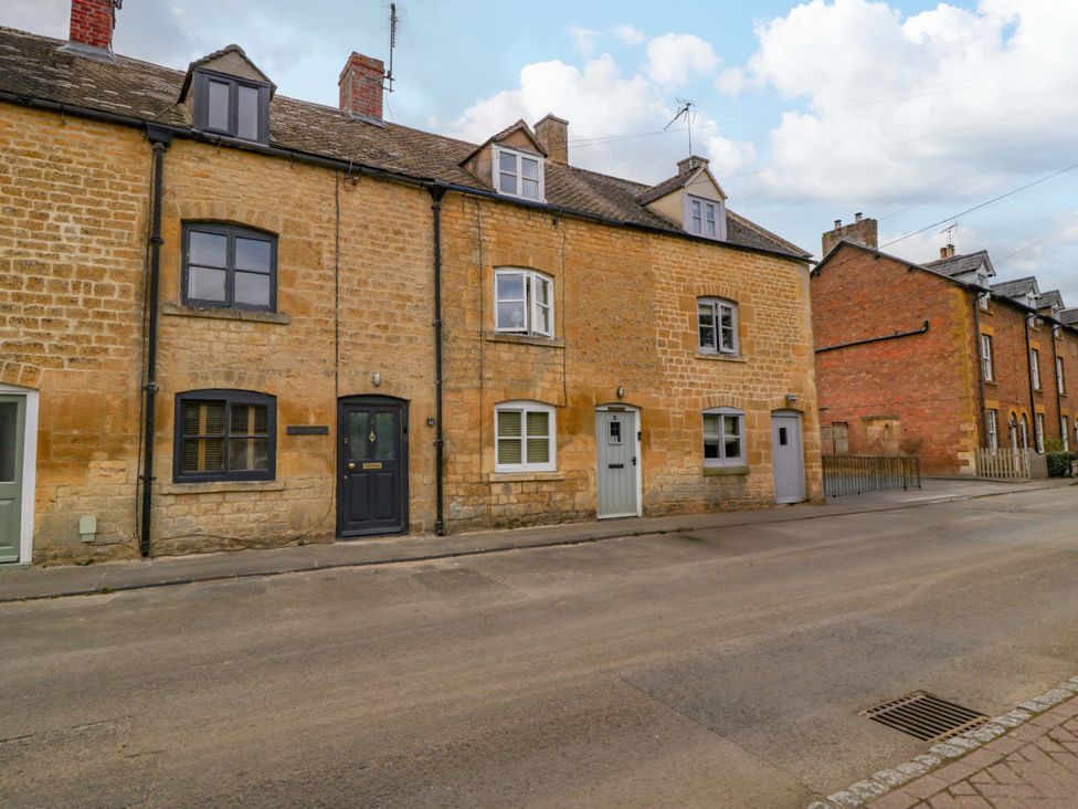 A stone building with multiple windows and doors on a street at Elm Cottage in Moreton-In-Marsh