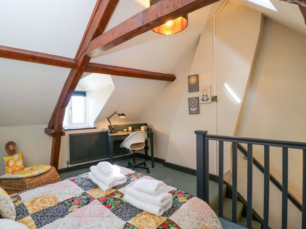 A bedroom with a bed and desk at Elm Cottage Moreton-In-Marsh