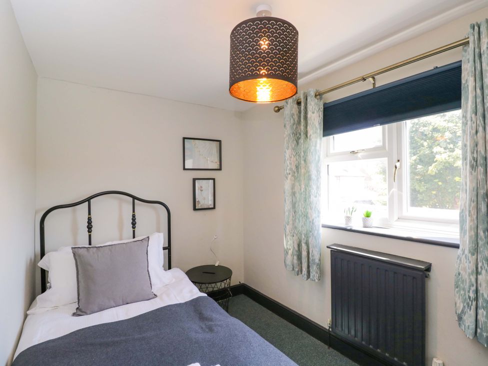 A bedroom with a bed and side table at Elm Cottage in Moreton-In-Marsh