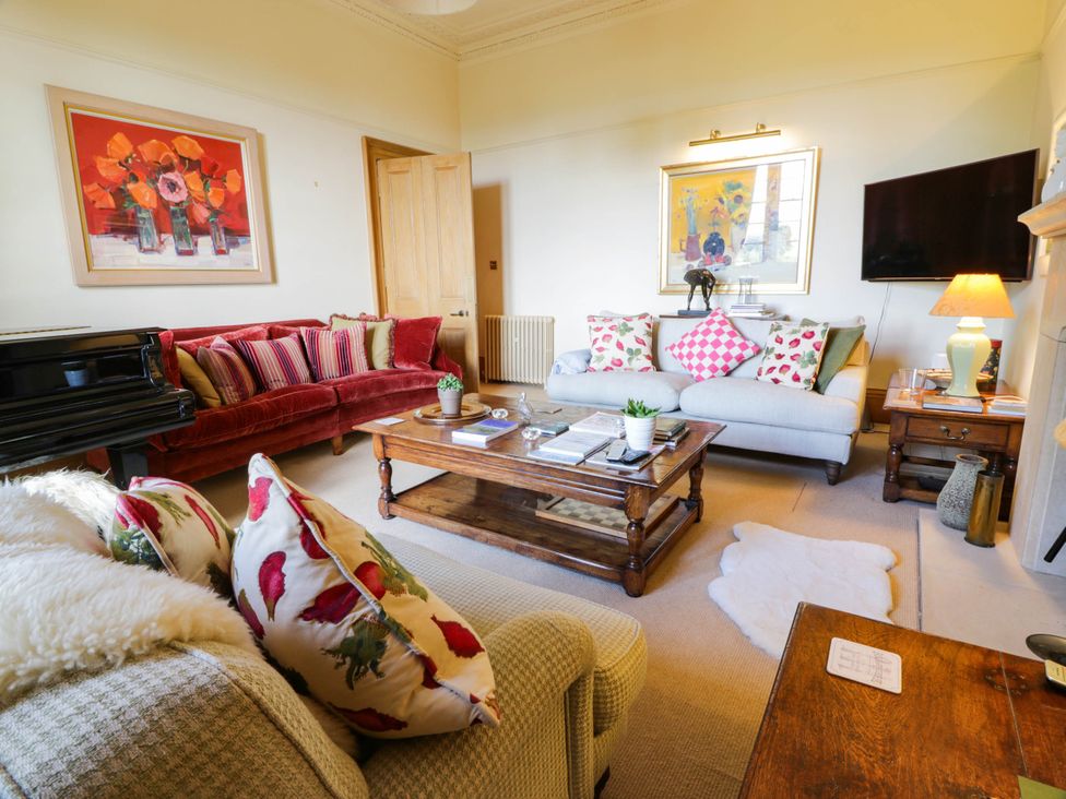 A living room with a piano and sofas at Eagle Glen Manor House in Blairgowrie
